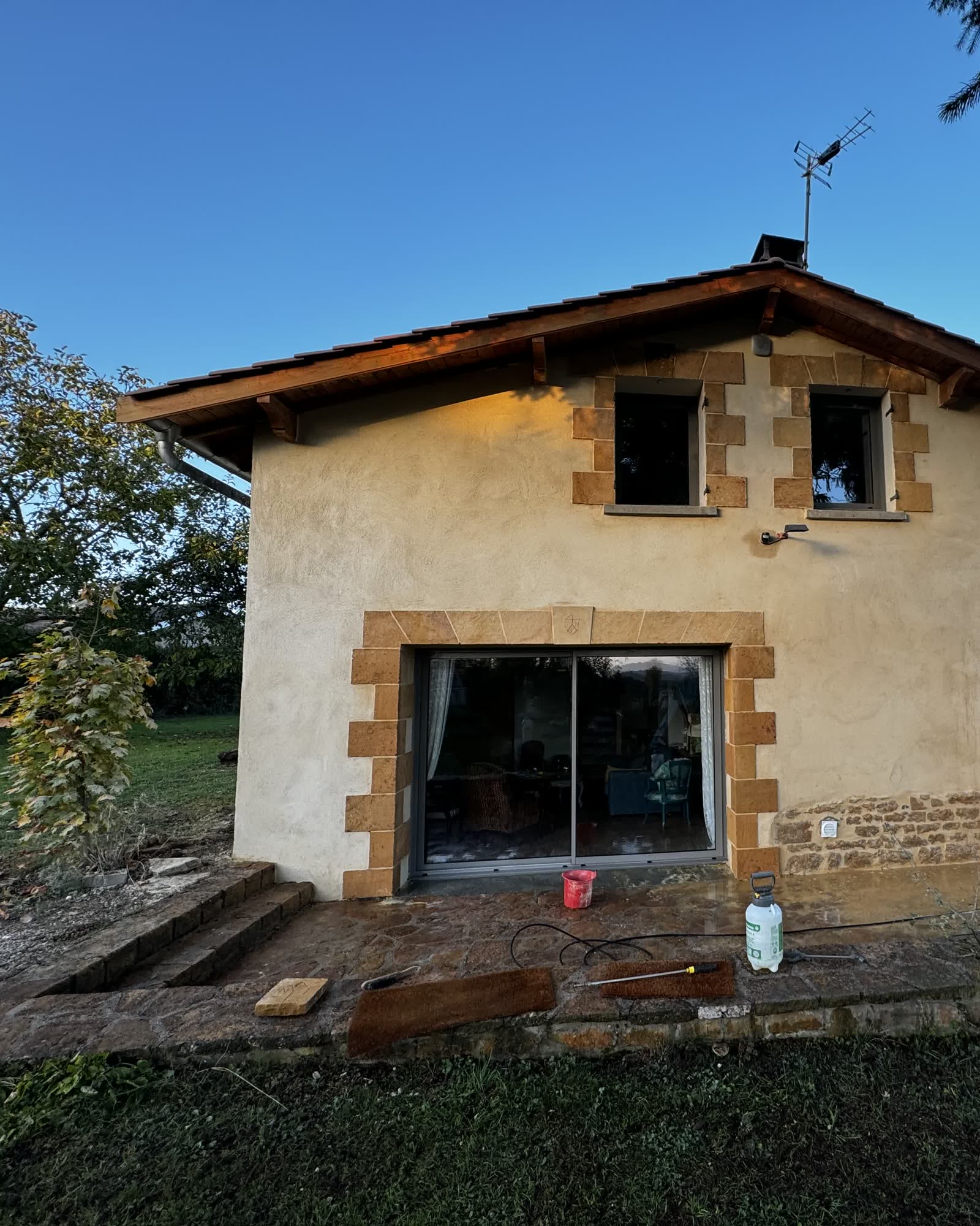 Pignon de maison rénové : façade enduite à la chaux, encadrements et appuis en pierre de taille, grande baie vitrée — après travaux