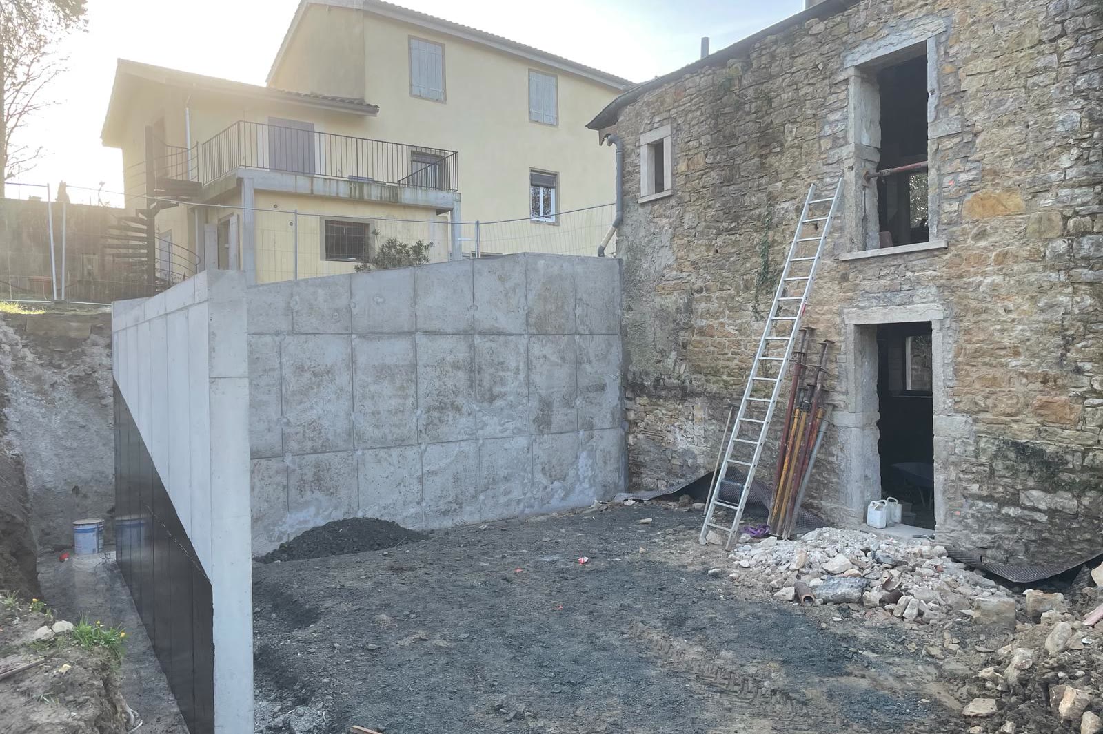 Cour : voile béton banché réalisé, reprise en sous-œuvre de la bâtisse en pierre — après travaux