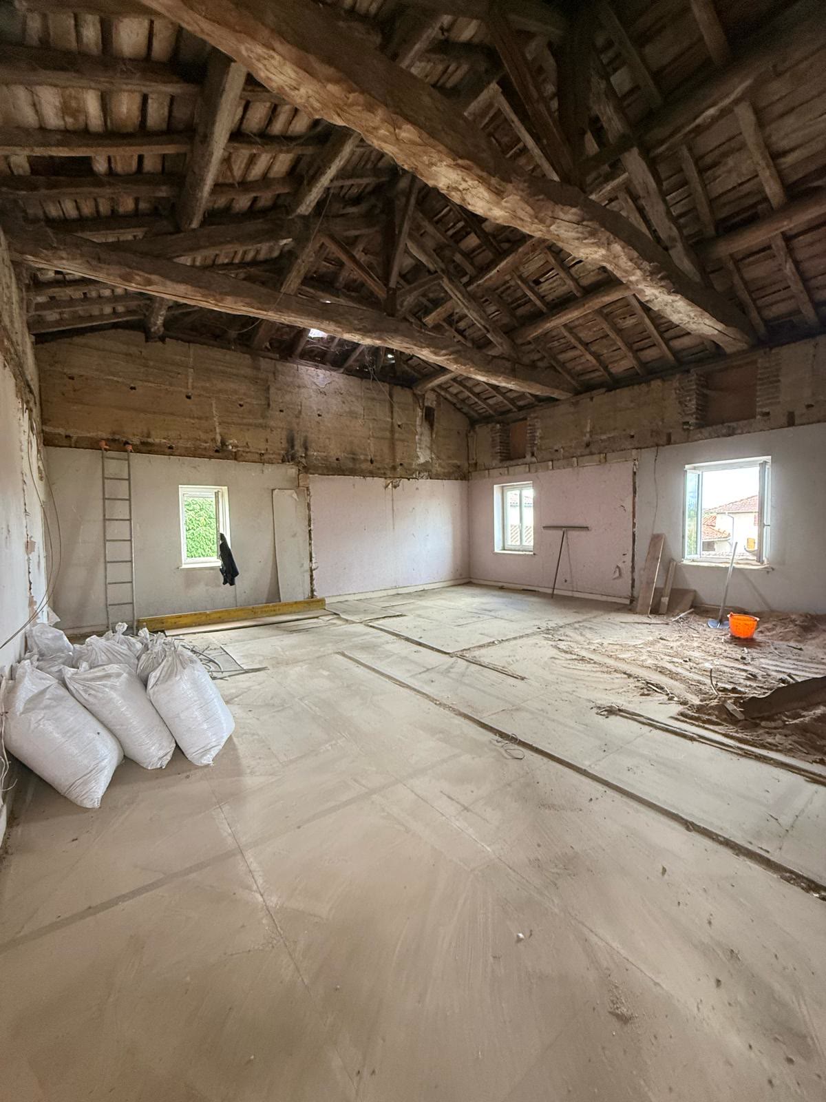 Intérieur du gîte communal après curage, charpente ancienne et dalle neuve